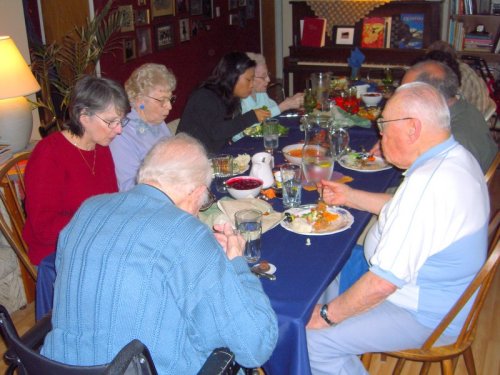 A group of people enjoying a meal together at a dining table, with various dishes and drinks in front of them.