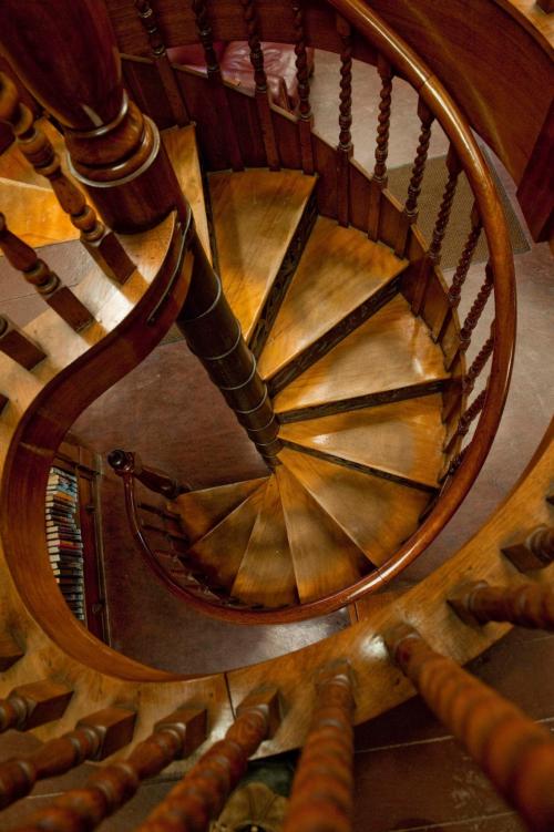 Aerial view of a wooden spiral staircase with ornate railings and polished steps.