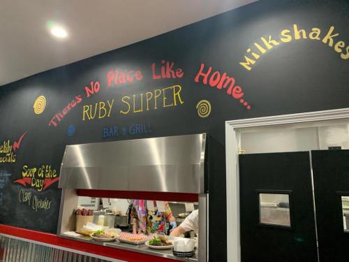 Colorful wall mural in a restaurant featuring the text "There's No Place Like Home... Ruby Slipper Bar & Grill."
