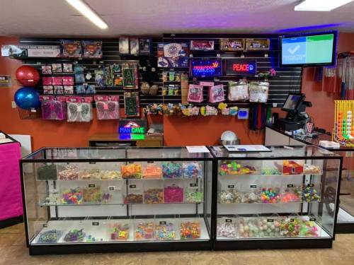A colorful store display featuring candy, toys, and novelty items, with bright signage and a cash register.