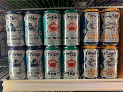 A shelf displaying various cans of Cape May Brewing Co. beers, including "Total Evacuation" and "Always Ready."