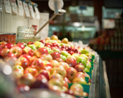 A vibrant display of red and green apples in baskets at a market, with blurred background details.
