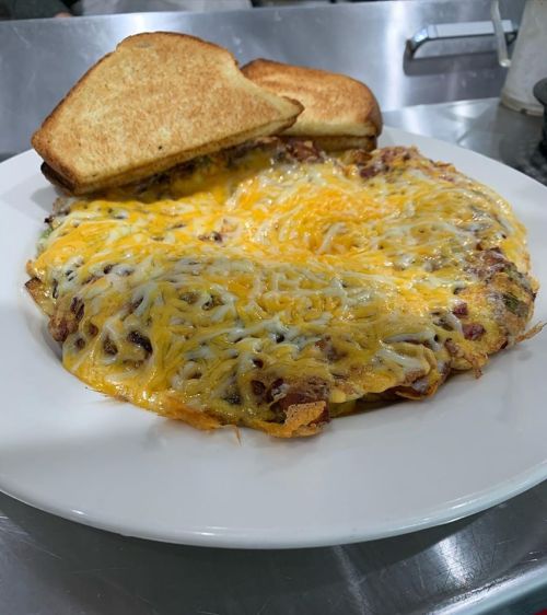A plate of cheesy omelette with toast on the side, served on a white dish.