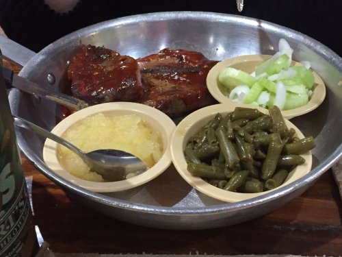 A metal plate with meatloaf, green beans, celery, and applesauce served in small bowls.