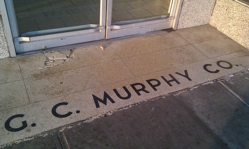 Text on a stone floor reads "G. C. Murphy Co." near a glass entrance.