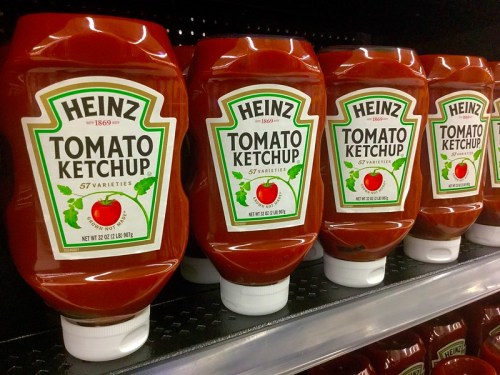 A row of Heinz Tomato Ketchup bottles on a store shelf, each labeled with "57 Varieties."