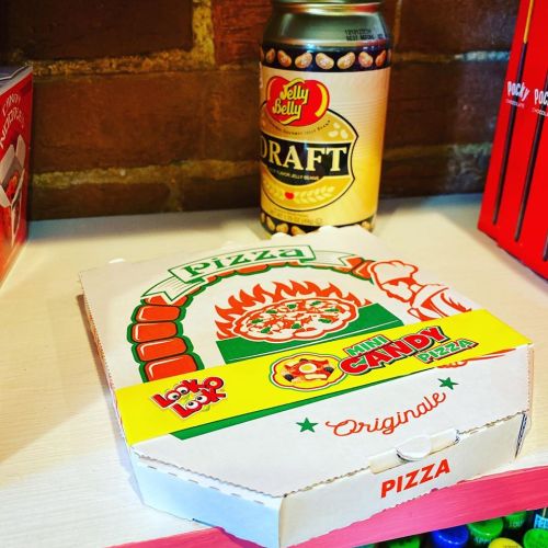 A colorful candy pizza box next to a can of Jelly Belly Draft soda on a shelf.