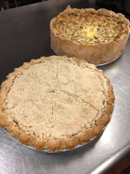 Two freshly baked pies on a metal surface: one with a crumbly topping and the other with a savory filling.