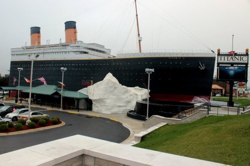 A large replica of the Titanic ship with an iceberg display, set against a cloudy sky.
