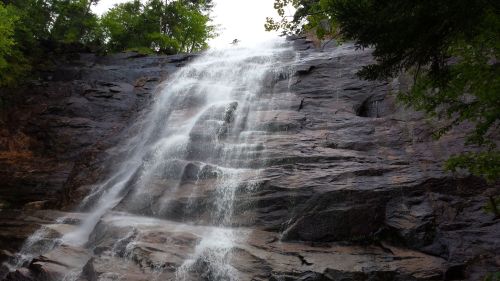 A cascading waterfall flows down a rocky cliff surrounded by lush greenery.