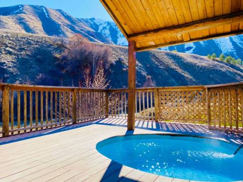 A wooden deck with a small pool overlooks a scenic mountain landscape under a clear blue sky.