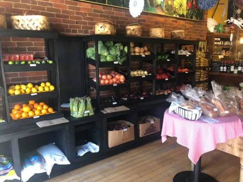 A vibrant market display with shelves of fresh fruits and vegetables, and a table with baked goods in a cozy setting.