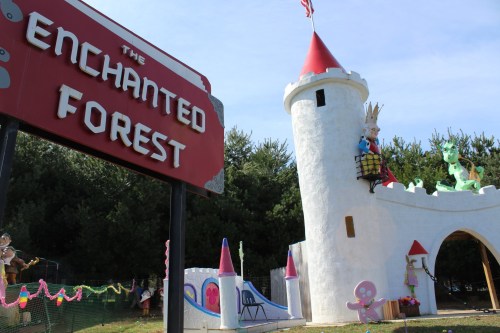 A whimsical castle with a dragon and a princess figure, next to a sign reading "The Enchanted Forest."