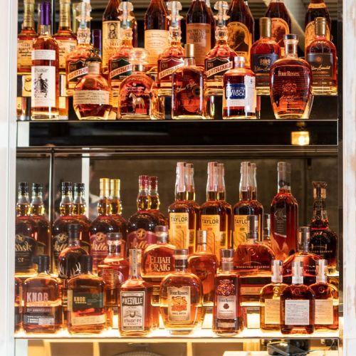 A display of various whiskey bottles arranged on shelves, showcasing a range of brands and styles.