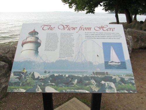 Sign describing the view from Cedar Point, featuring a lighthouse, roller coasters, and a sailboat on the water.