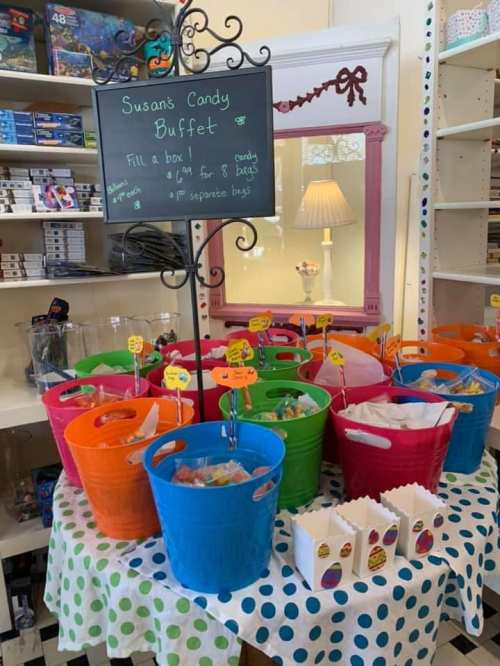 Colorful candy buffet with baskets filled with sweets, a sign offering candy boxes, and a polka dot tablecloth.