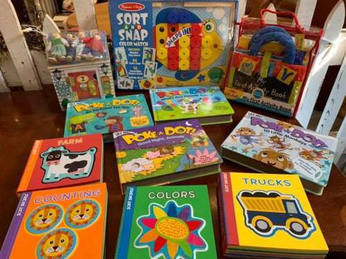 A colorful collection of children's books and toys, including activity books and a sorting game.