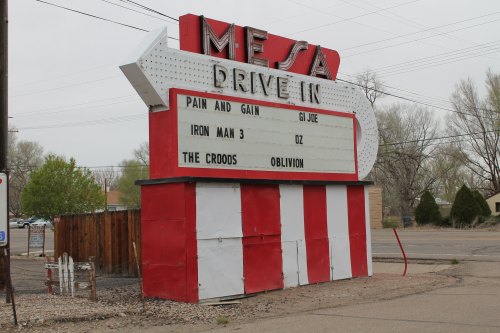 A vintage drive-in movie theater marquee displaying film titles like "Pain and Gain," "G.I. Joe," and "Iron Man 3."