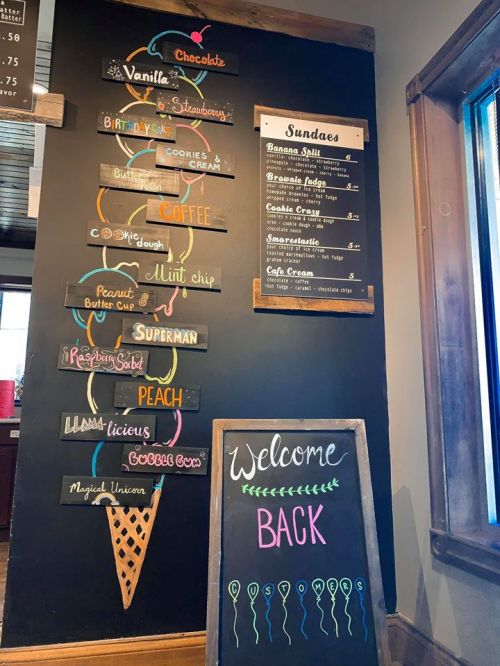 Chalkboard menu featuring ice cream flavors and sundaes, with a "Welcome Back" sign in colorful chalk.