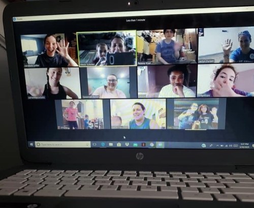 A group of people waving during a virtual meeting on a laptop screen.