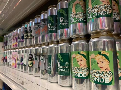 A shelf displaying various colorful beer cans with unique labels, including "Bellevue Blonde" and "Biggie Smalls."