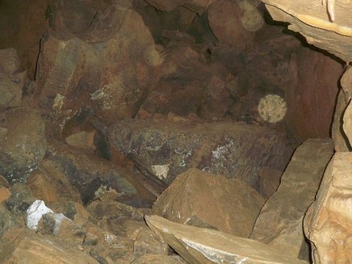 A rocky cave interior filled with large boulders and debris, creating a dark and rugged environment.