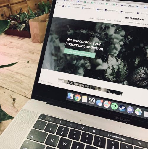 A laptop displaying a website for "The Plant Shack," promoting houseplant shopping and addiction.