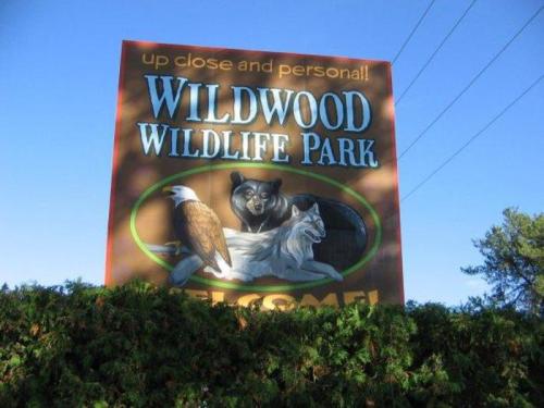 Sign for Wildwood Wildlife Park featuring a bear, eagle, and wolf, with the text "up close and personal! Welcome!"
