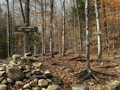 Trail signs for Bemis Brook and Appalachian Trail in a wooded area with autumn leaves and rocky terrain.