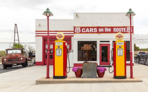 Vintage gas station with retro pumps, featuring a classic car nearby, set along Route 66.