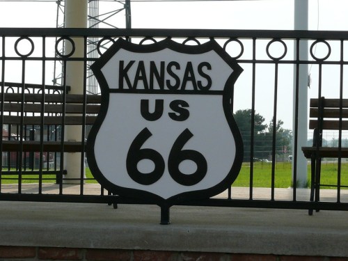 Sign for Kansas section of US Route 66, featuring a classic shield design on a railing.