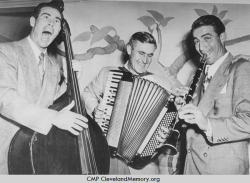 Three musicians joyfully playing instruments: a double bass, accordion, and clarinet, in a vintage setting.