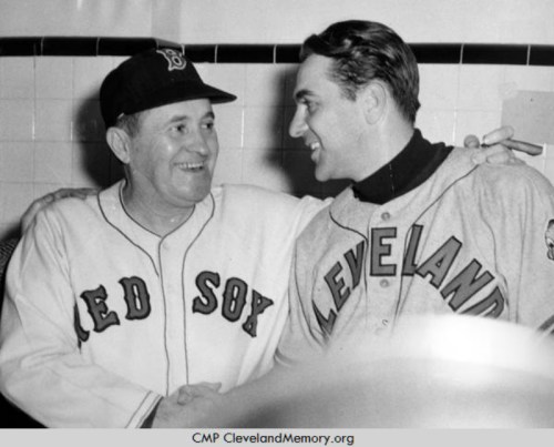 Two baseball players in team jerseys, one from the Red Sox and the other from Cleveland, smiling and shaking hands.