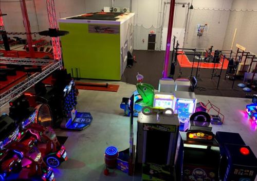 A vibrant indoor entertainment center featuring arcade games, a basketball court, and climbing walls.