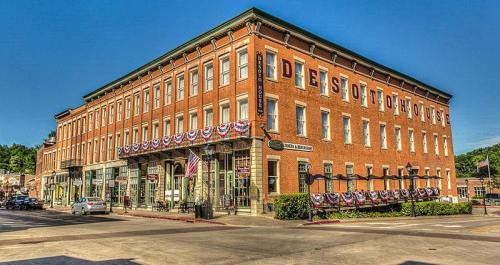 Historic DeSoto House Hotel with red brick facade, flags, and bunting, located at a street corner in a quaint town.