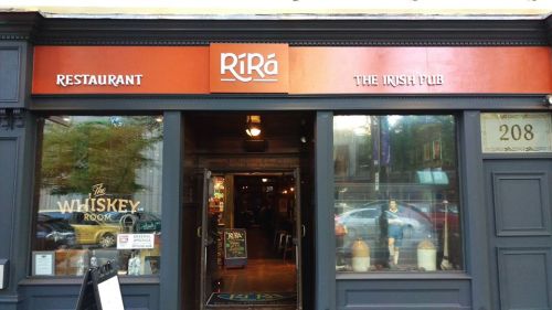 Entrance of Rí Rá Irish Pub, featuring a sign and a view into the cozy interior with wooden decor.