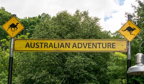 Sign reading "Australian Adventure" with kangaroo icons on either side, set against a backdrop of green trees.