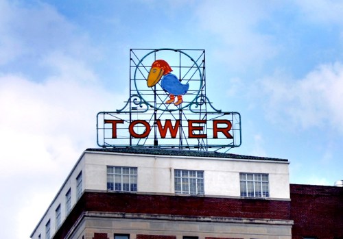 Colorful sign featuring a cartoon bird and the word "TOWER" against a blue sky.