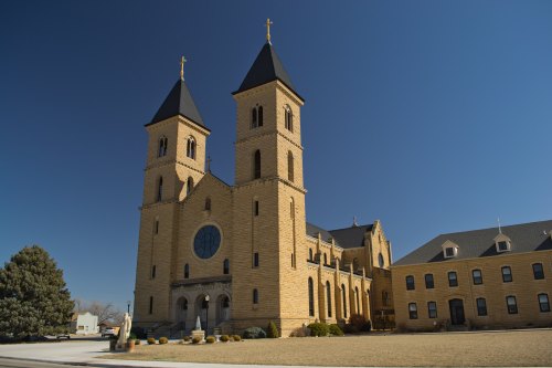 Historic stone church with twin towers and a large circular window, set against a clear blue sky.