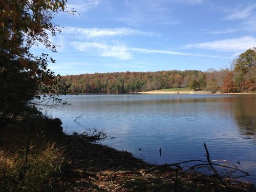 A serene lake surrounded by autumn foliage under a clear blue sky, with gentle ripples on the water's surface.