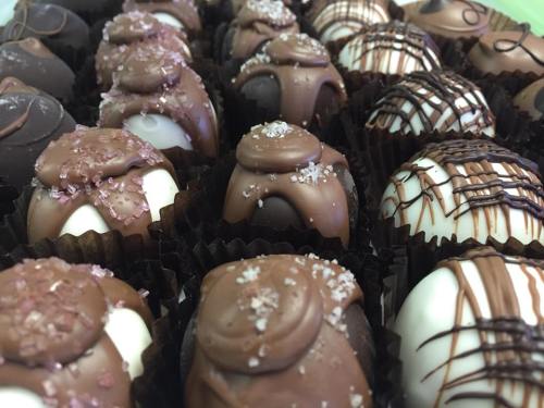 A close-up of assorted chocolate truffles, featuring dark and white chocolate with decorative toppings.
