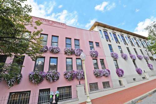 Two buildings with colorful flower boxes, one pink and one white, under a blue sky with scattered clouds.
