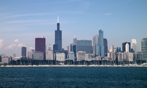 Chicago skyline featuring tall buildings and a clear blue sky, with boats docked along the waterfront.