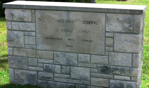 Stone monument with engraved text: "The Clarence H. Geist Reservoir, Fall Creek Supply, Indianapolis Water Company, 1943."