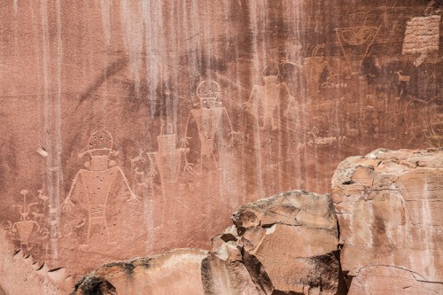 Petroglyphs on a rock face depicting human figures and animals, showcasing ancient art and cultural heritage.