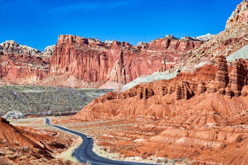 A winding road through vibrant red rock formations under a clear blue sky.