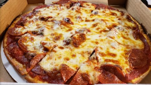 A close-up of a pepperoni pizza with melted cheese, served in a pizza box.
