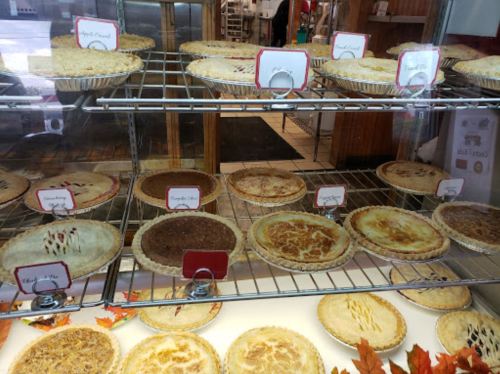A display case filled with various pies, each labeled with names, showcasing a variety of flavors and crusts.