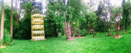 A lush green park featuring unique sculptures, including a tall spiral structure and various artistic installations.