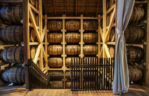 A wooden storage area filled with stacked barrels, with a staircase leading down in the foreground.